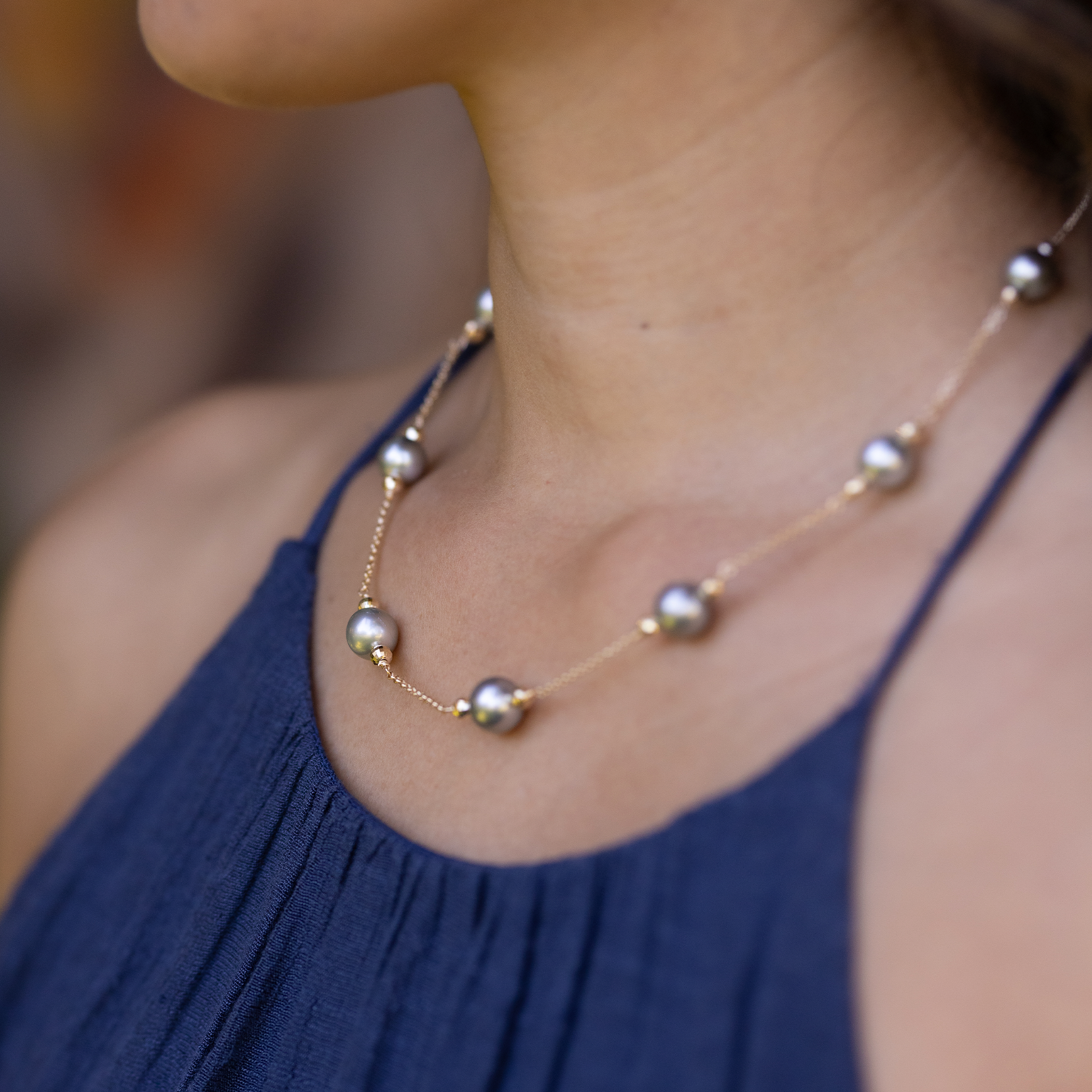 Close-up of a woman wearing a Tahitian black pearl necklace in yellow gold.