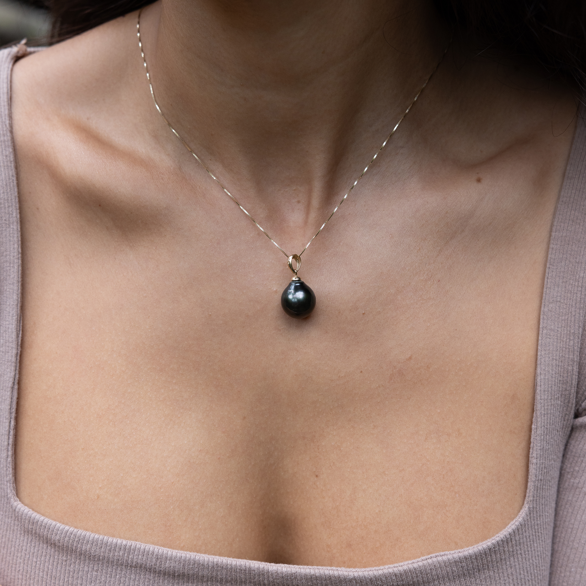 Close-up of a woman wearing a drop-shape Tahitian black pearl pendant.