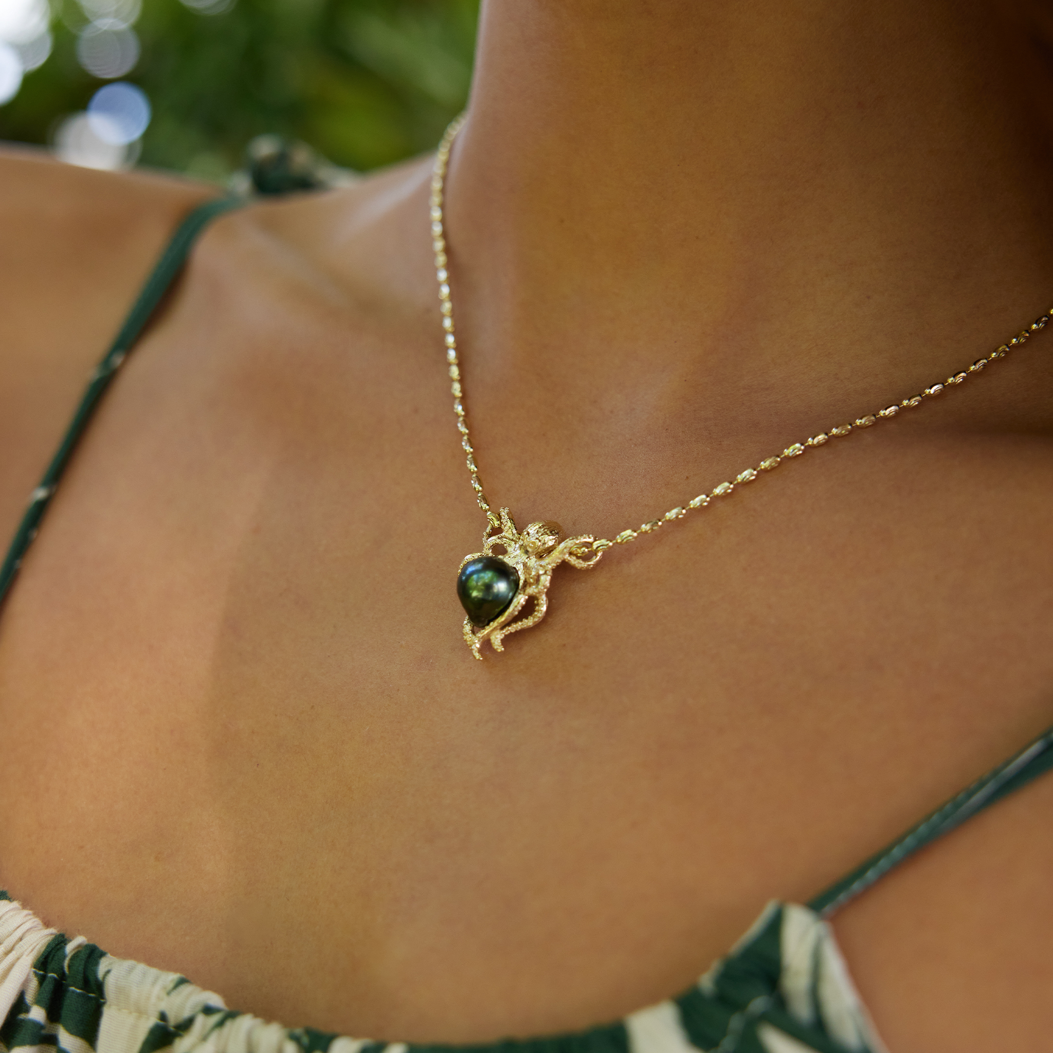 Close-up of a person wearing a Octopus Tahitian black pearl pendant in 14k yellow gold.