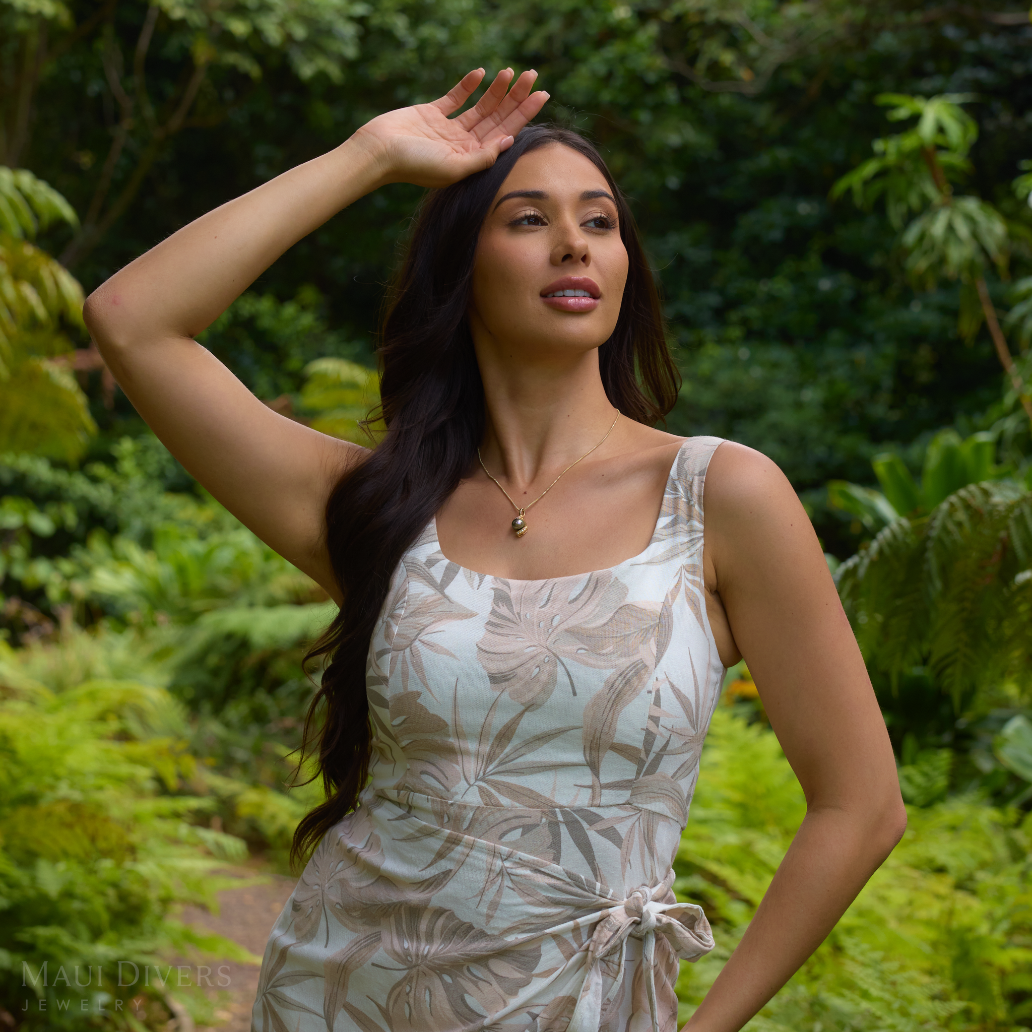 Woman in a white patterned dress wearing a Tahitian black pearl necklace in a garden