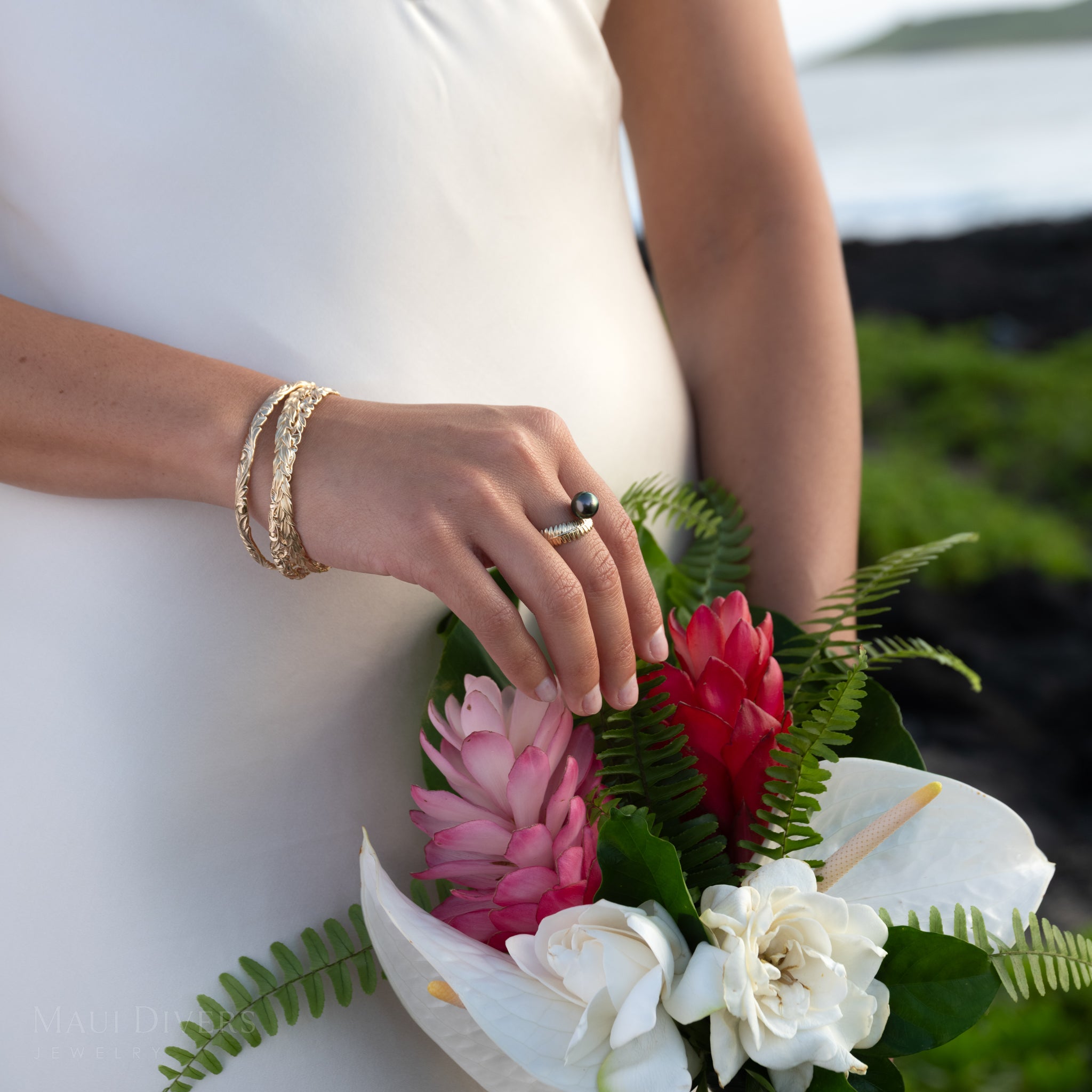 Bouquet of flowers held by a person wearing a gold Kupukupu Fern Tahitian Black Pearl Ring and Hawaiian bracelets
