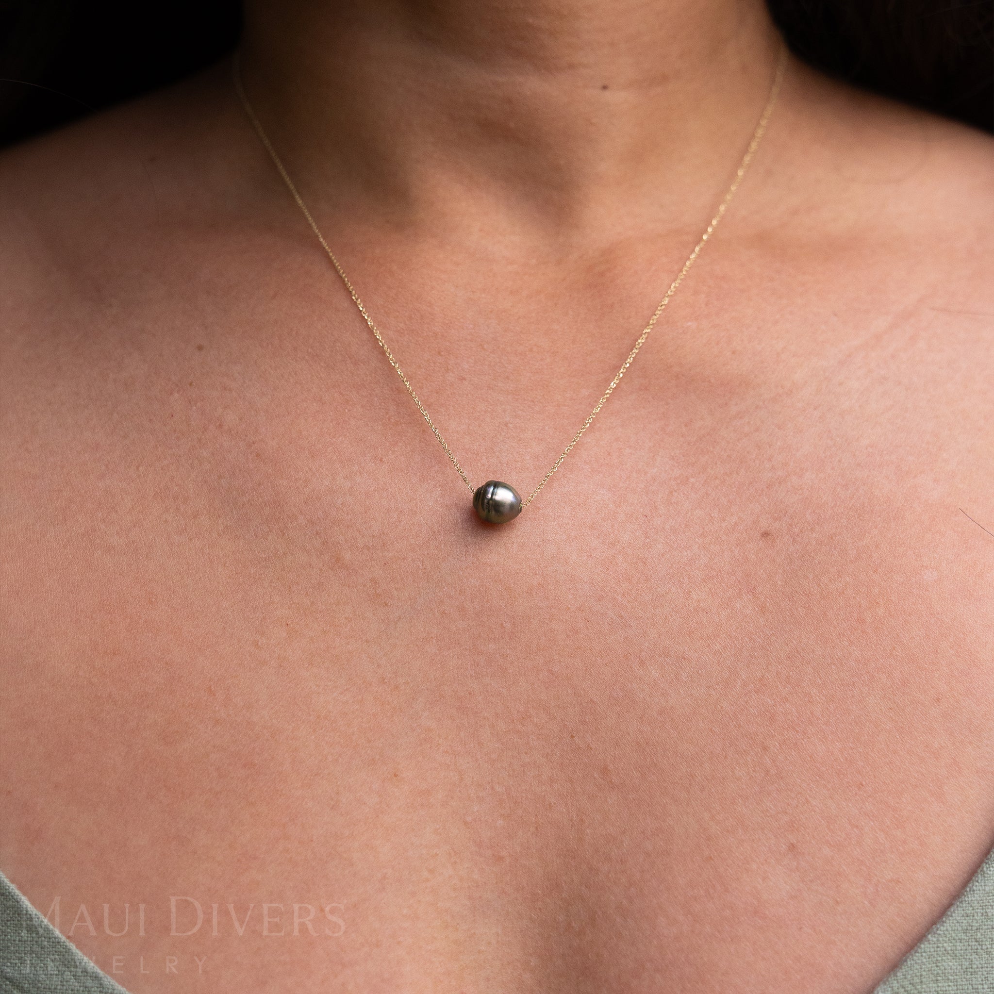 Close-up of an Adjustable Tahitian Black Pearl Necklace in 14k yellow gold worn on a neck