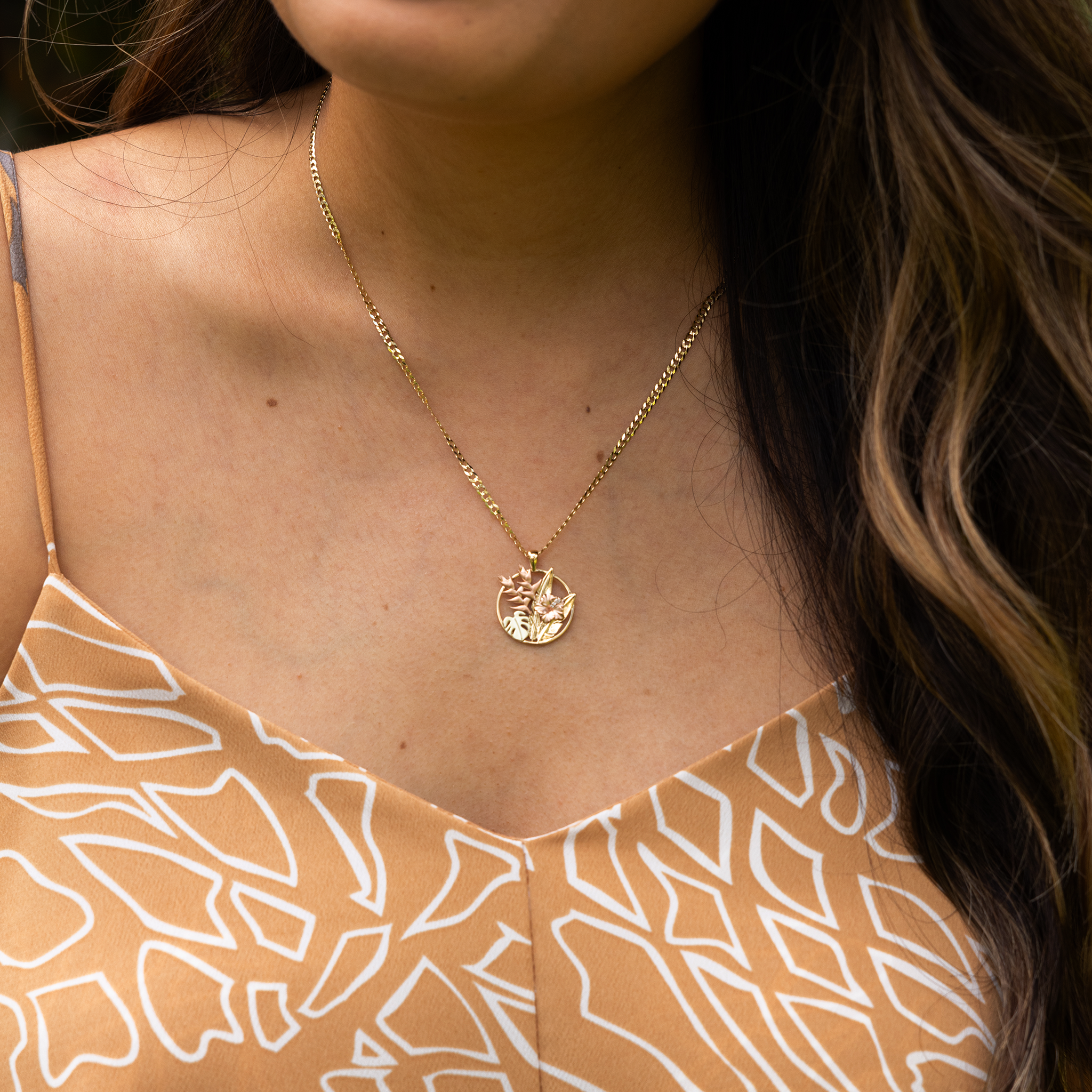 Close up of a woman wearing a Hawaiian Gardens Hibiscus Pendant in Tri Color Gold with Diamonds
