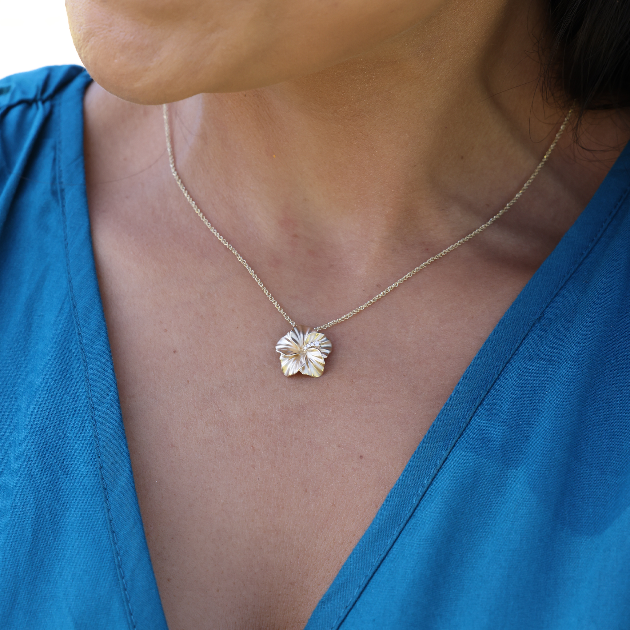 Close up of a person wearing the diamond hibiscus pendant