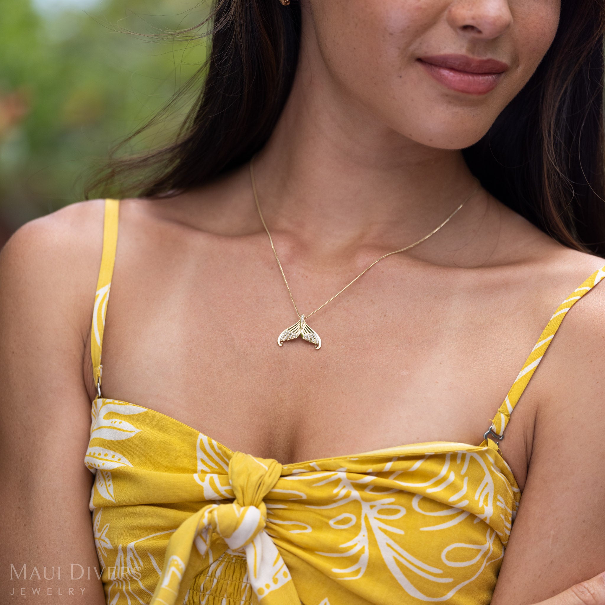 Close-up of a neckline with a 14k Gold Mermaid Tail Necklace with Natural Diamond accents.