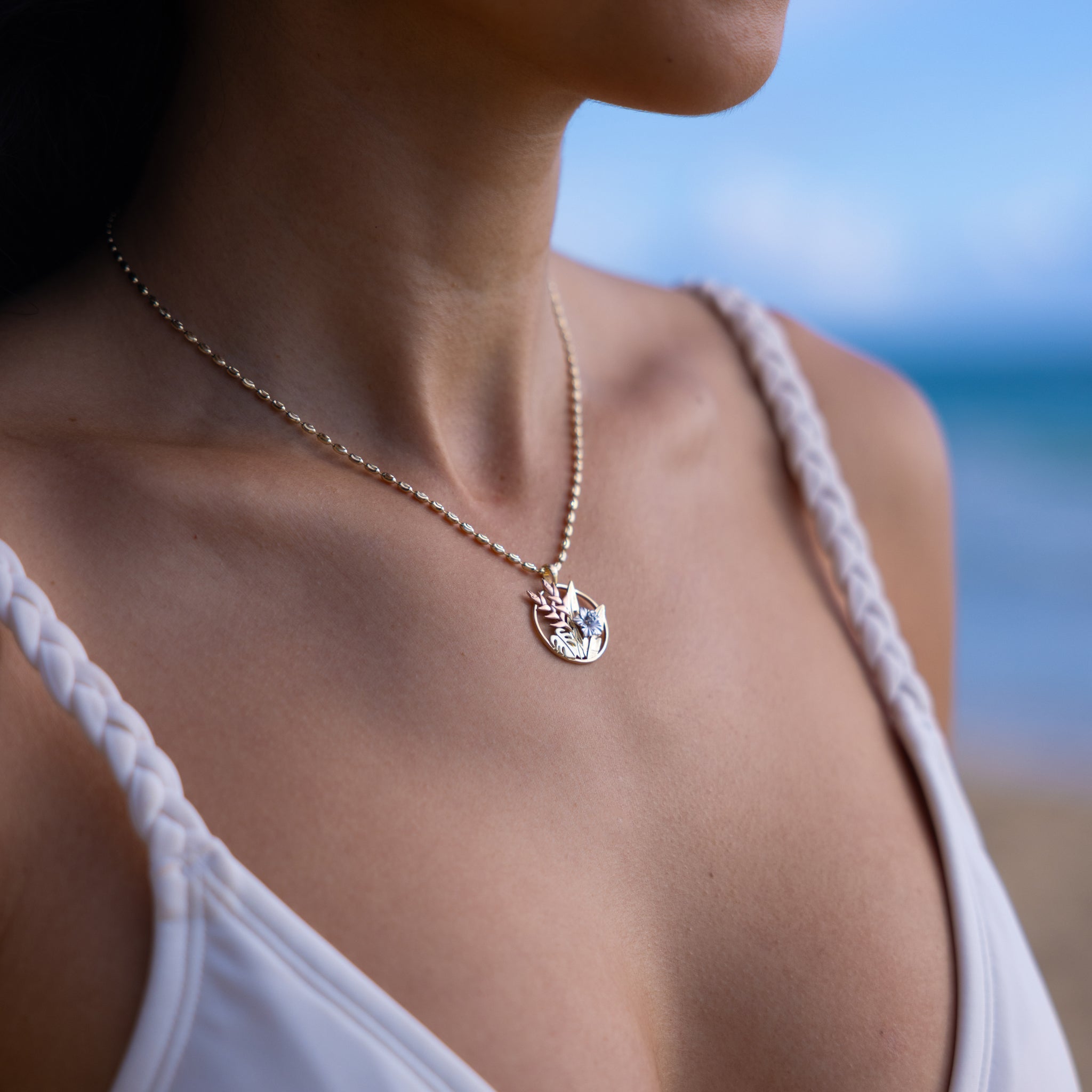 Close up of woman wearing Hawaiian Gardens Pendant in four tone gold with diamonds