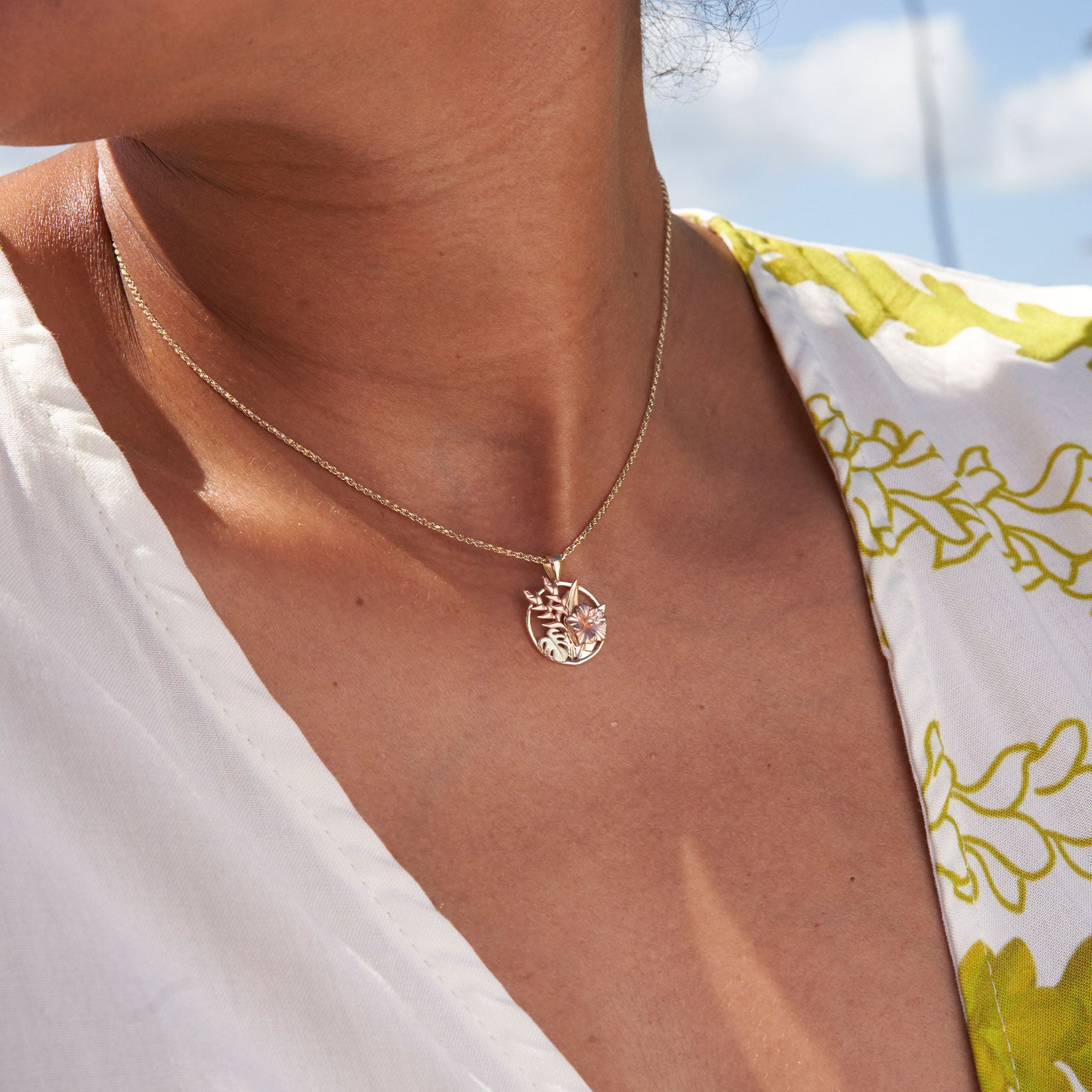 Close up of woman wearing Hibiscus, Heliconia and Monstera Pendant in Tri-color gold with diamonds