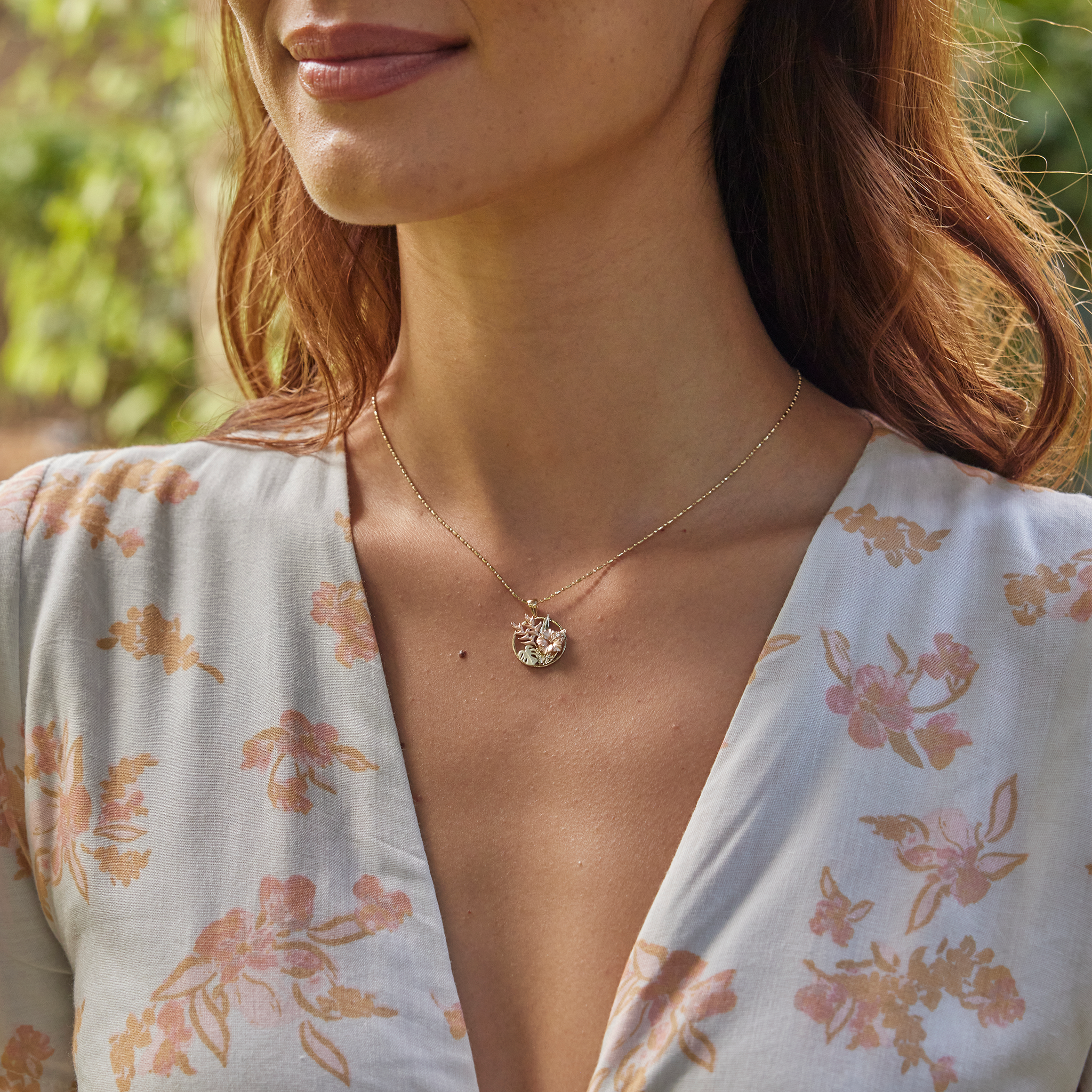 Close up of woman wearing Hibiscus, Heliconia and Monstera Pendant in Tri-color gold with diamonds