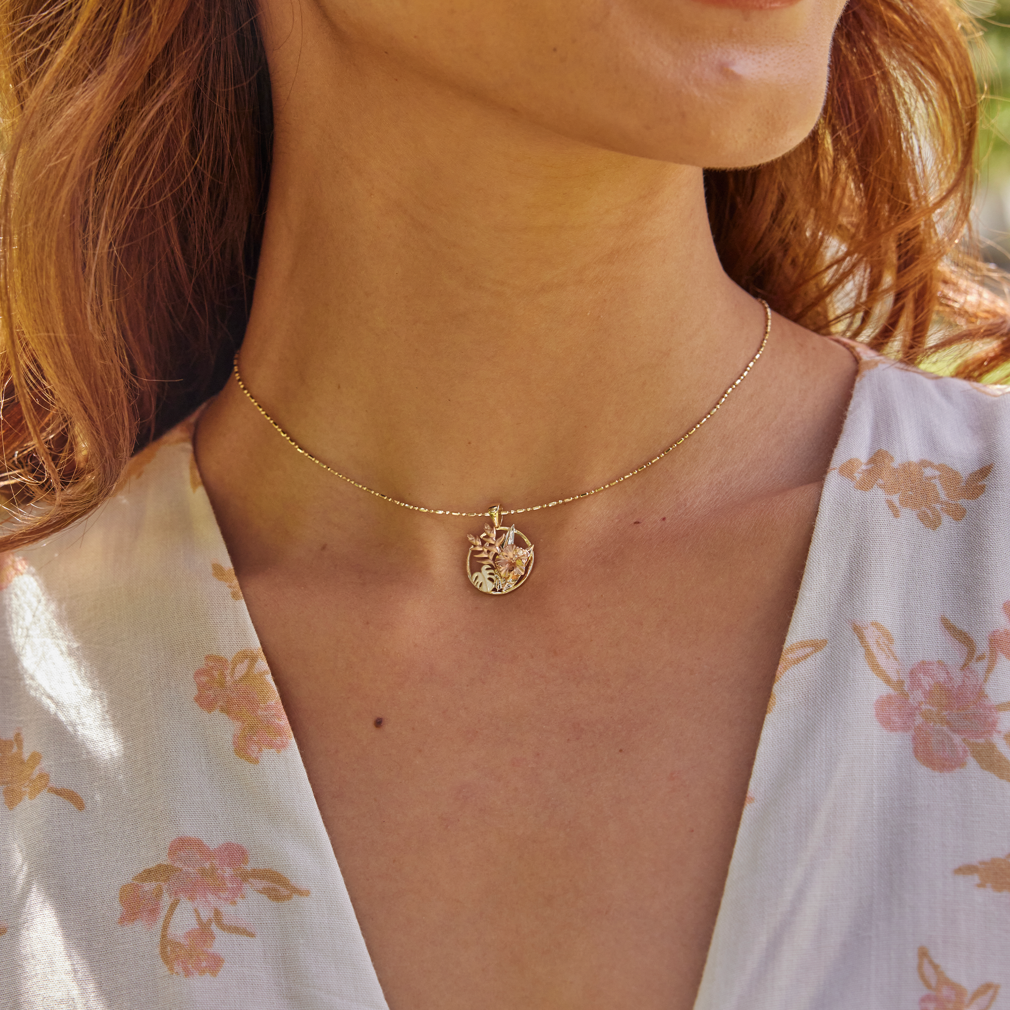 Close up of woman wearing Hibiscus, Heliconia and Monstera Pendant in Tri-color gold with diamonds