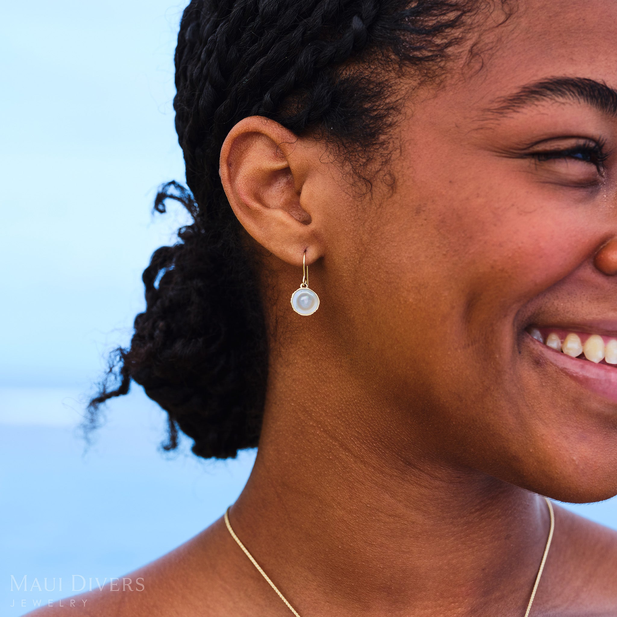 Close-up of a woman outdoors wearing a Coconut Earring with Mother of Pearl center and Gold outer husk