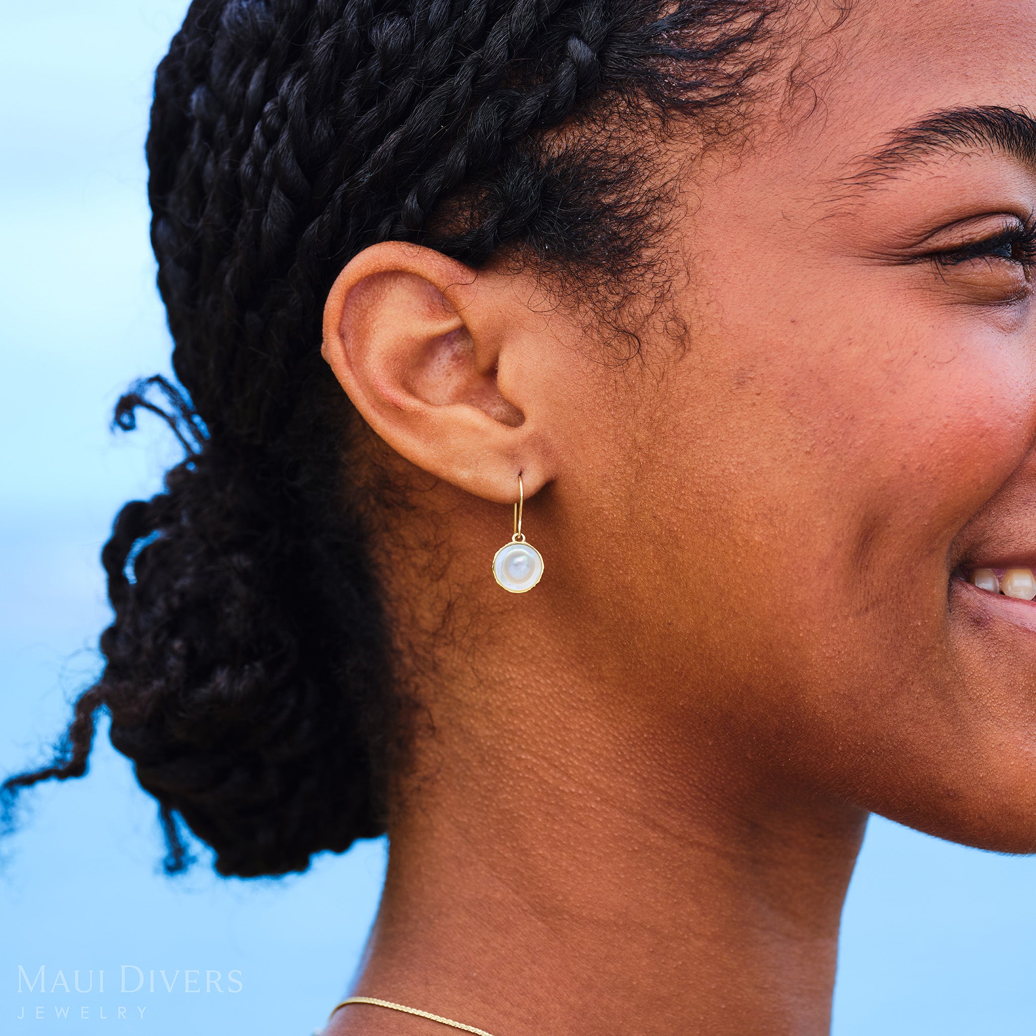 Close-up of a woman outdoors wearing a Coconut Earring with Mother of Pearl center and Gold outer husk