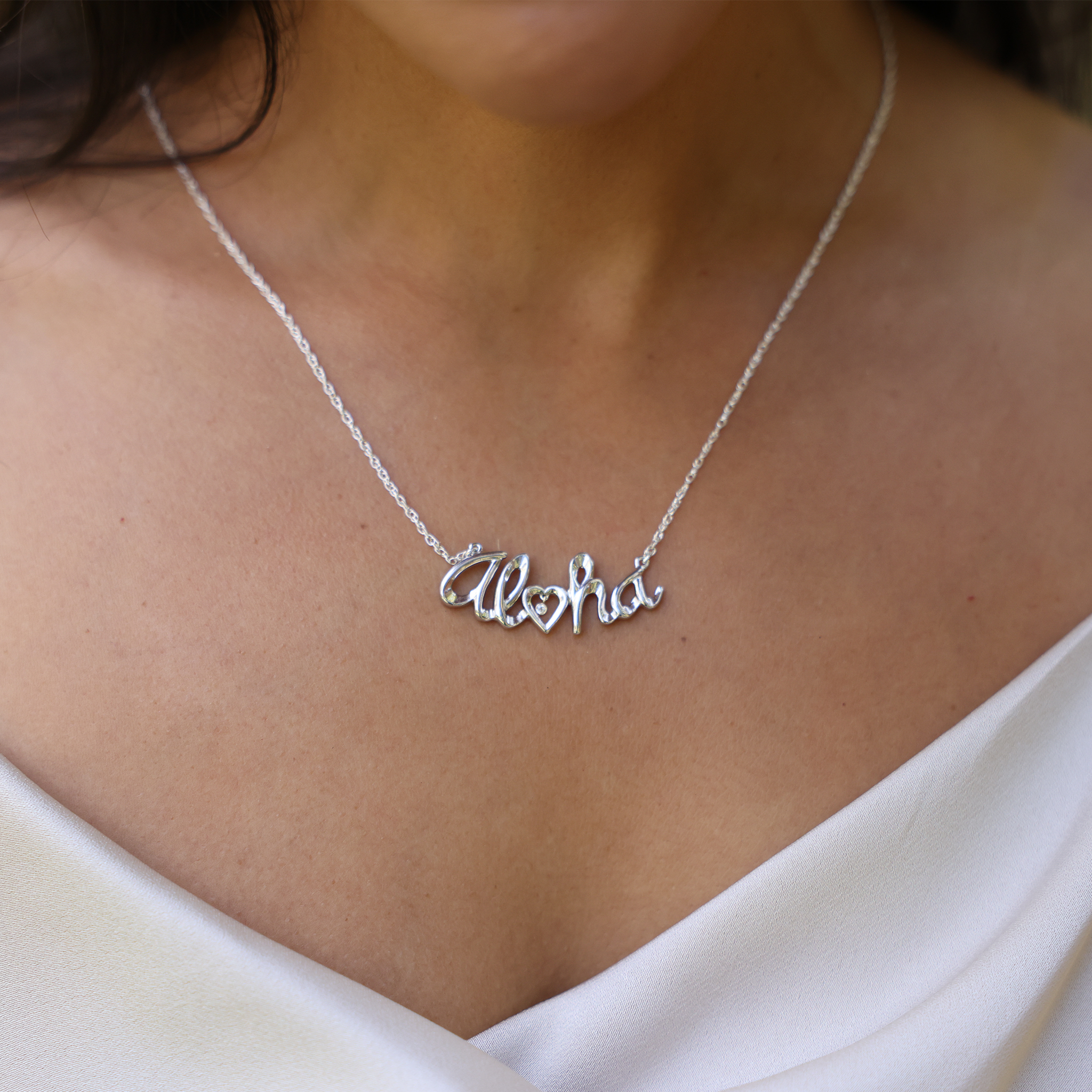 Close up of Aloha Necklace in Sterling Silver with Diamond bezel set in Gold on a woman's chest
