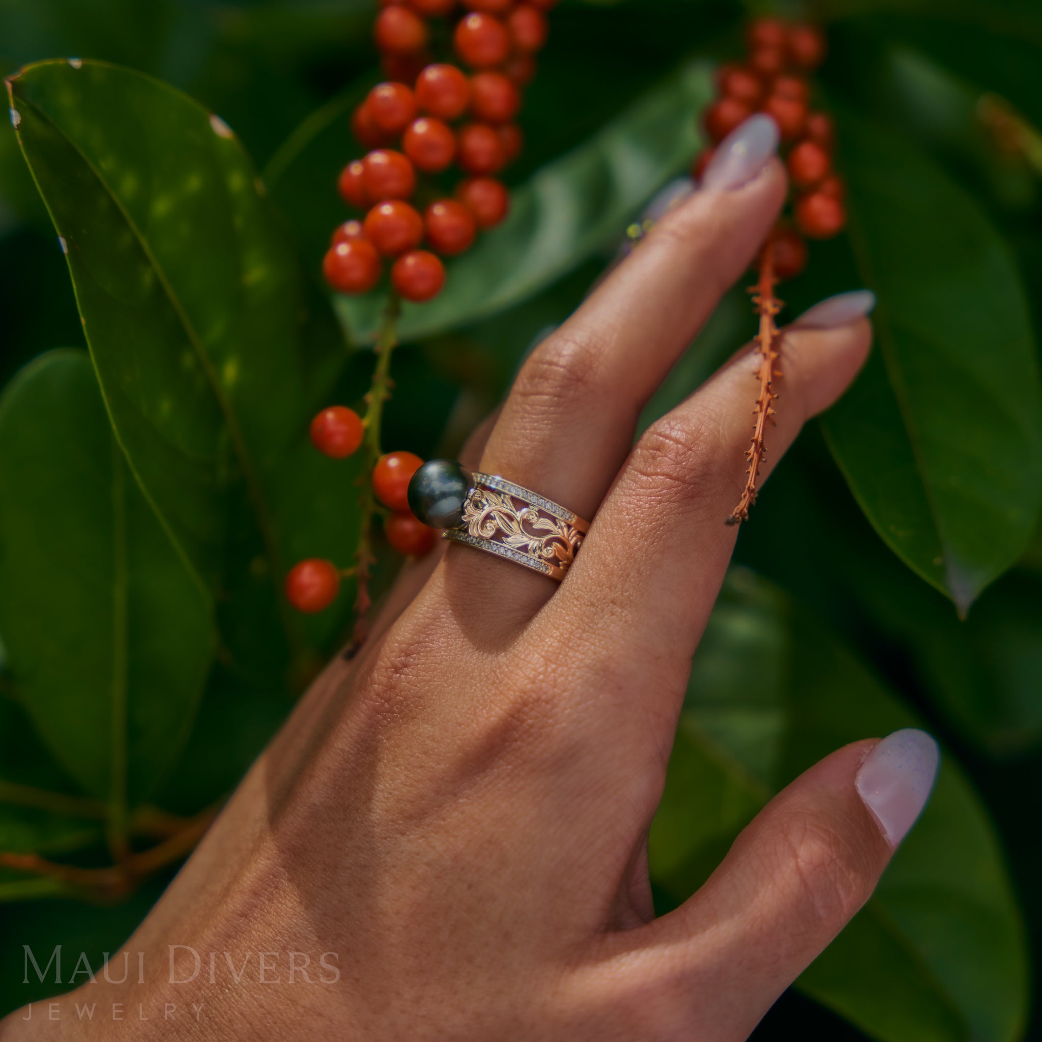 Hand wearing a Living Heirloom Tahitian Black Pearl Ring in Gold with Diamonds with berries and leaves in the background