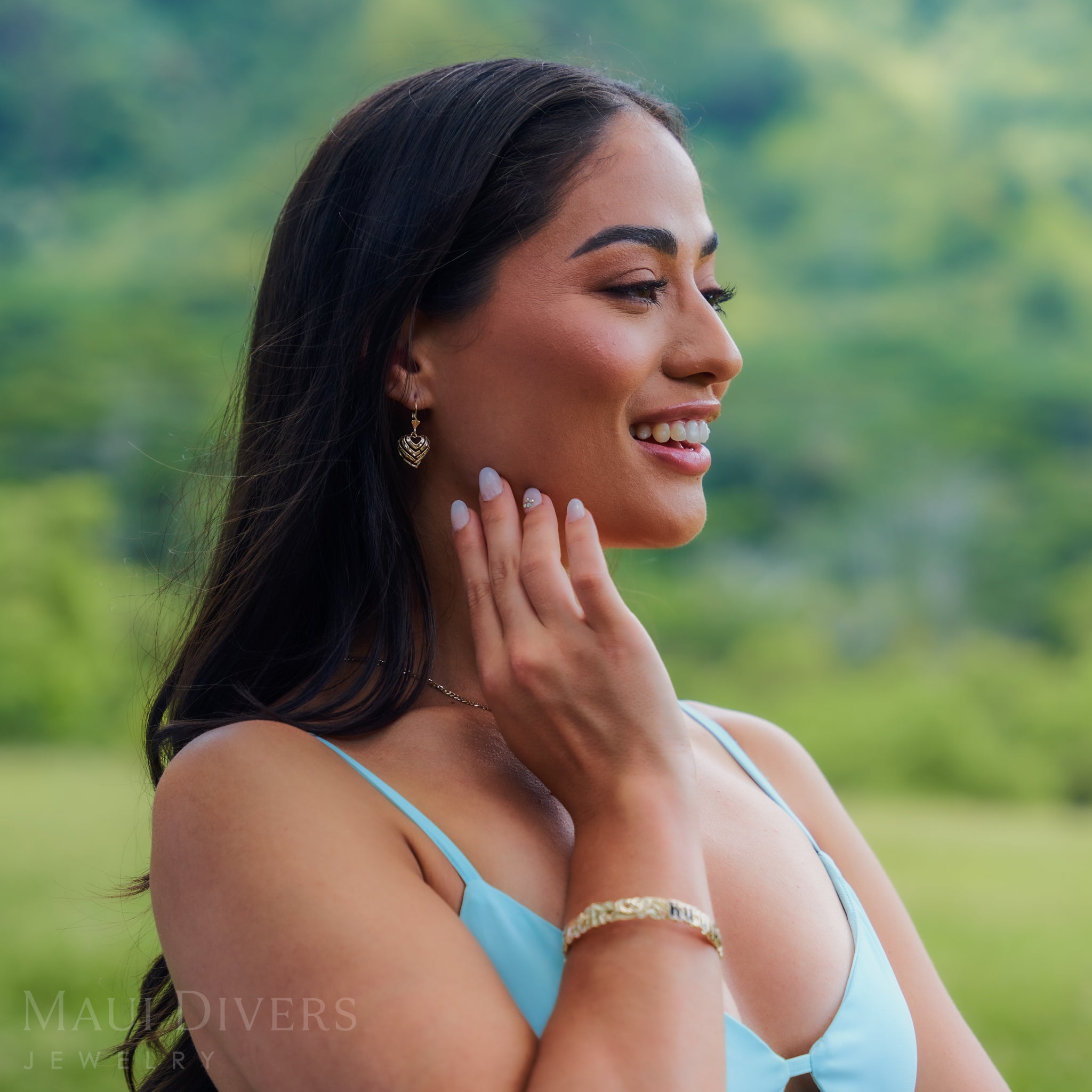 Woman outdoors wearing 15mm Aloha Heart Fleur de Lis Leverback Earrings in 14k Yellow Gold