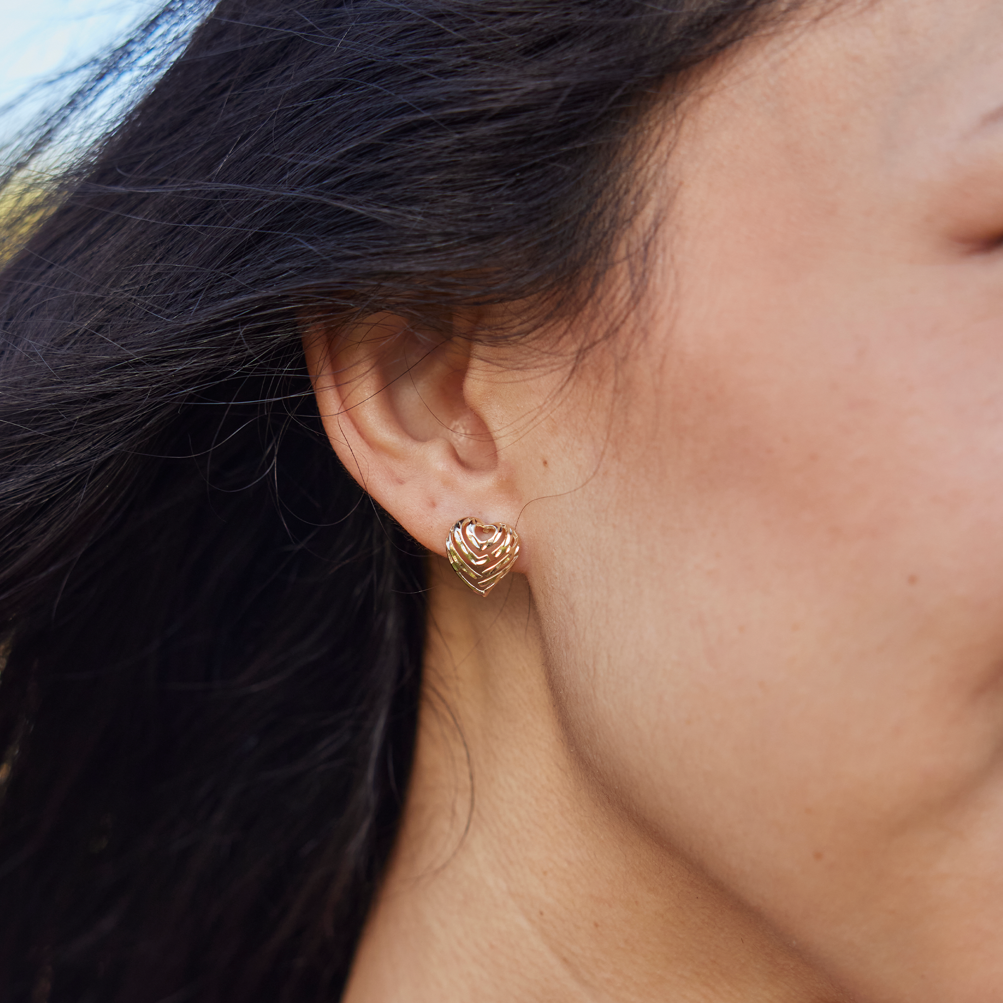 Close up of 11mm Aloha Heart Earrings in Gold on ear