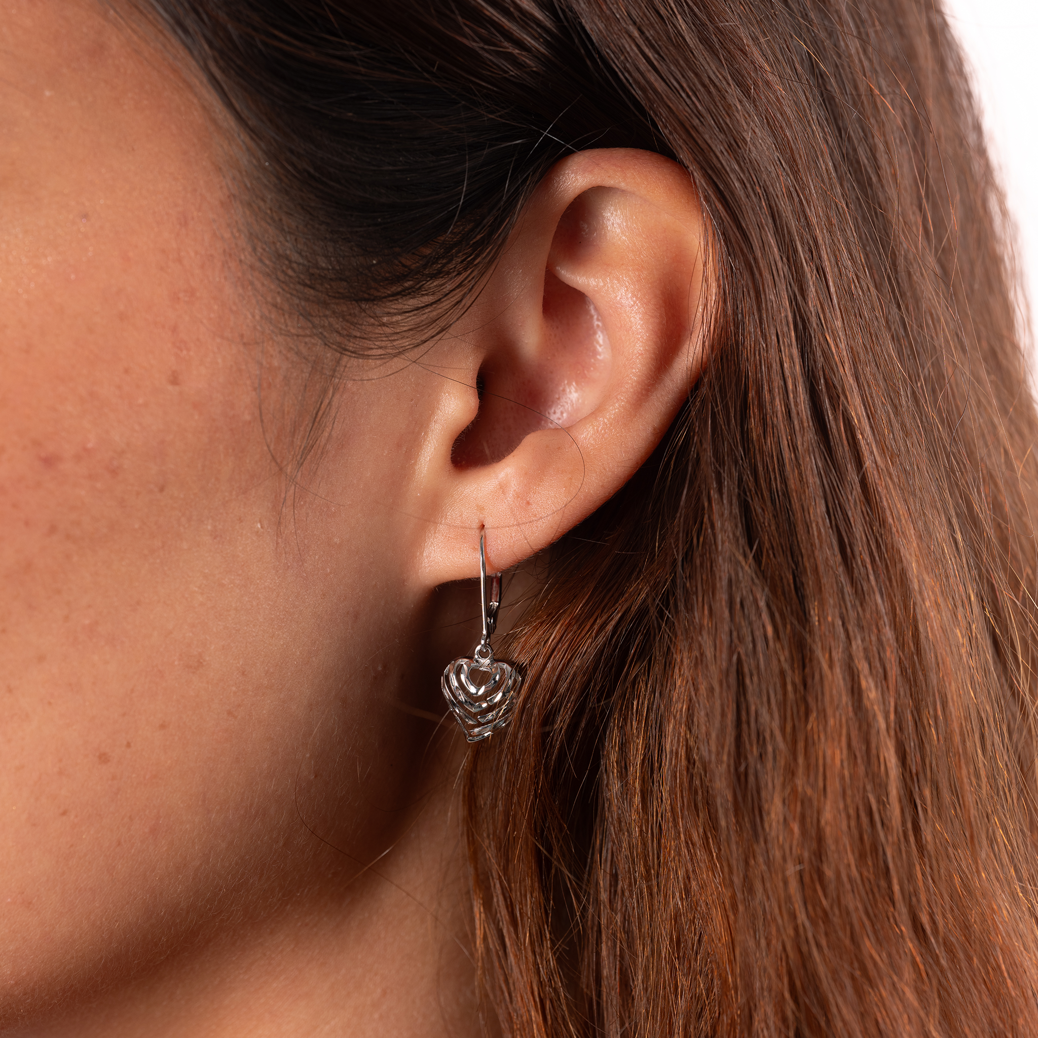 Close up of 11mm Aloha Heart Earrings in White Gold on ear