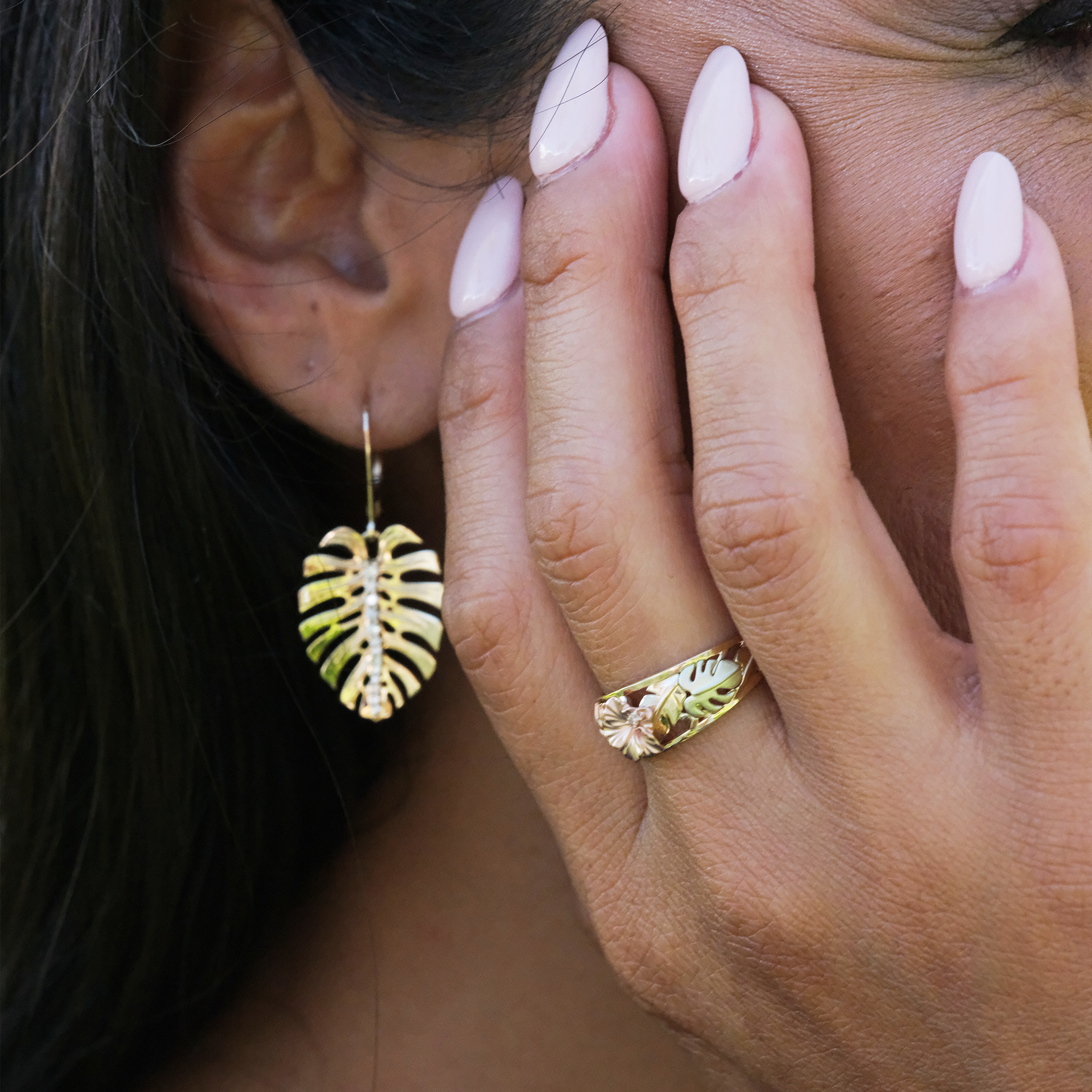 A woman wearing a Hawaiian Gardens Hibiscus Ring in Tri Color Gold with Diamonds and Monstera earrings