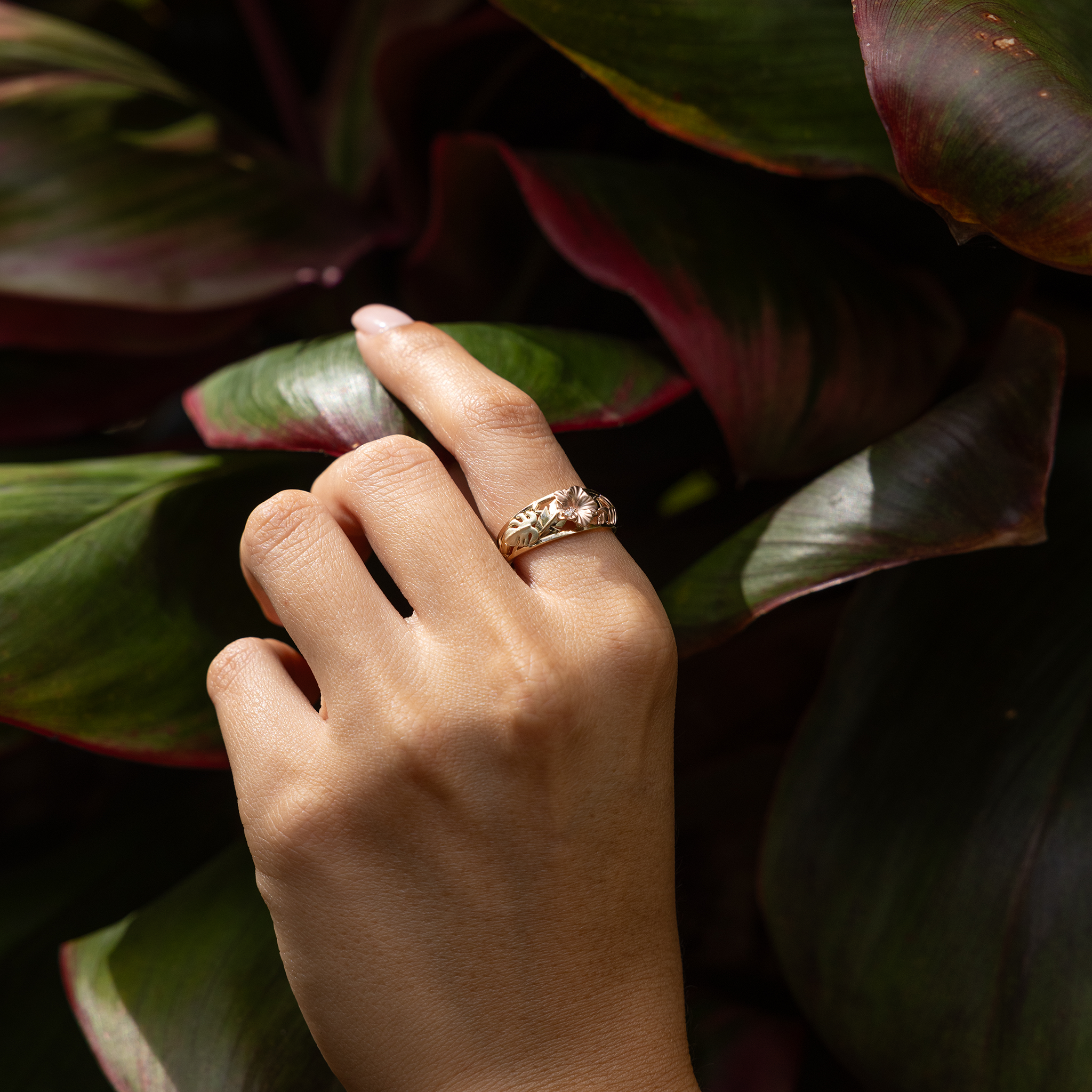 Hawaiian Gardens Hibiscus Ring in 14k Yellow, Rose, and Green Gold with Diamonds on hand touching ti leaves