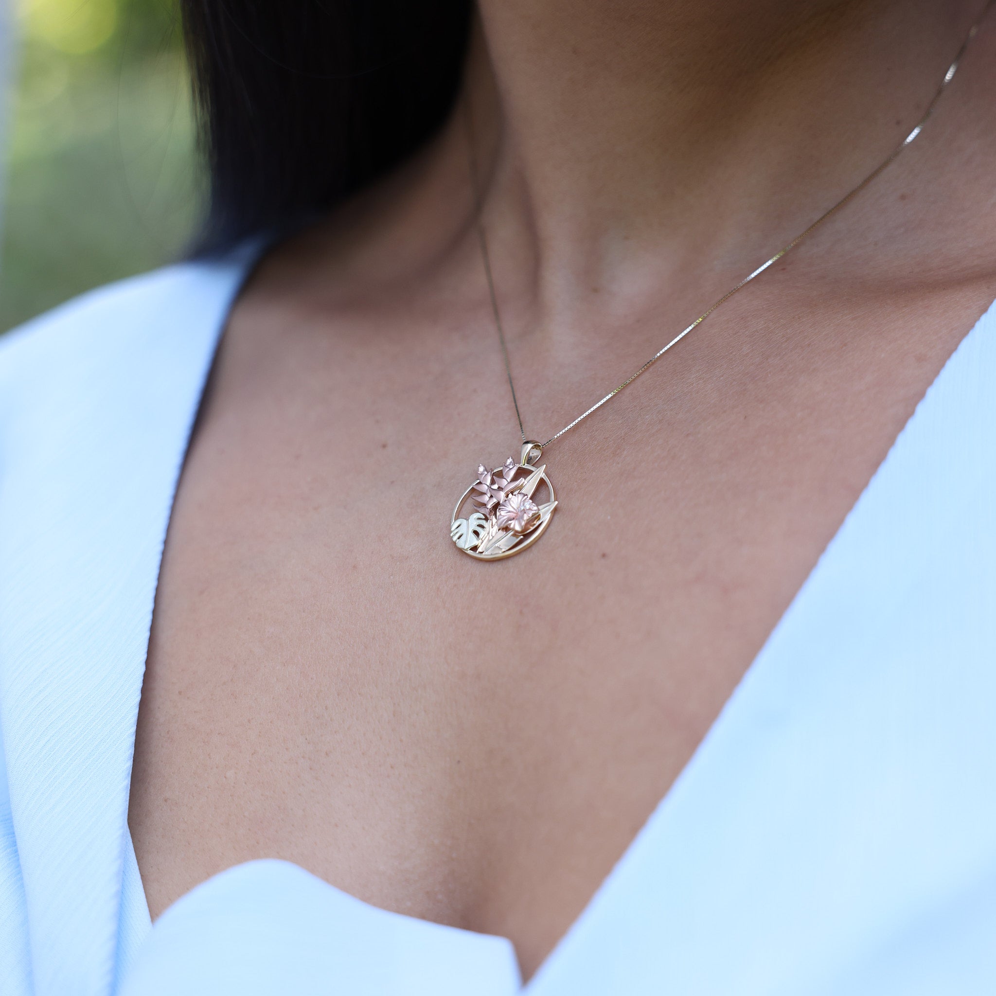 Close up of a woman wearing a Hawaiian Gardens Hibiscus Pendant in Tri Color Gold with Diamonds