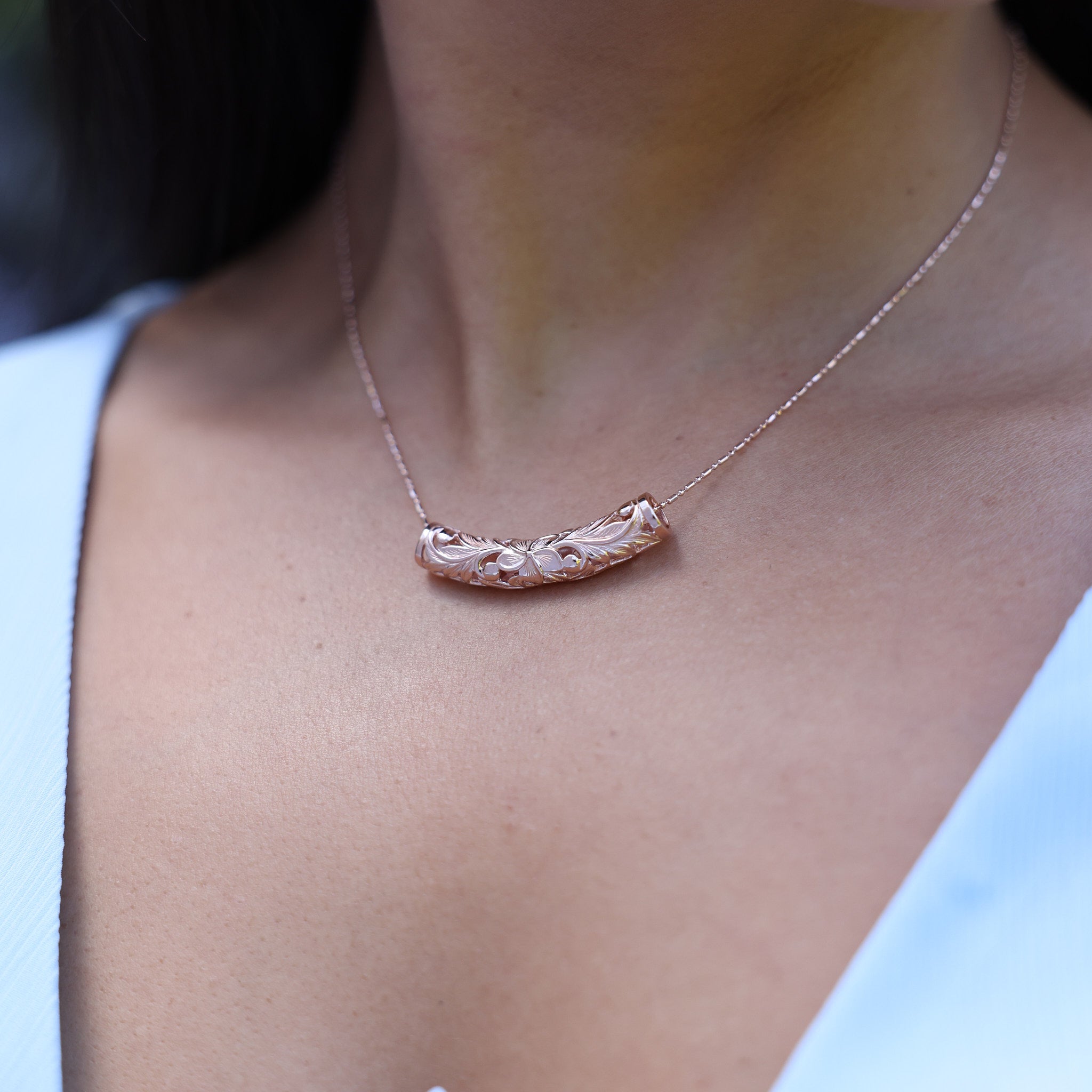 Close up of 1.0mm Ball Bar Chain in Rose Gold with a barrel pendant on a womanʻs chest