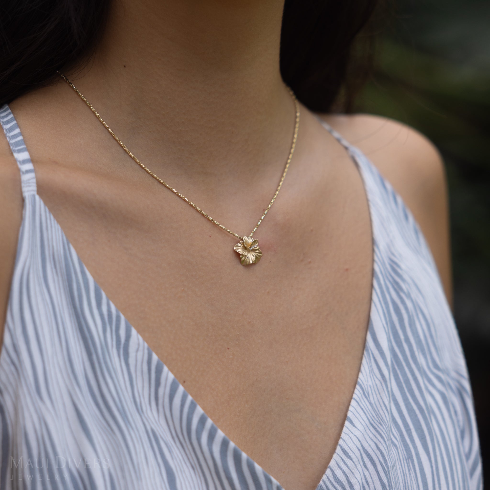 Close up of a person wearing the diamond hibiscus pendant