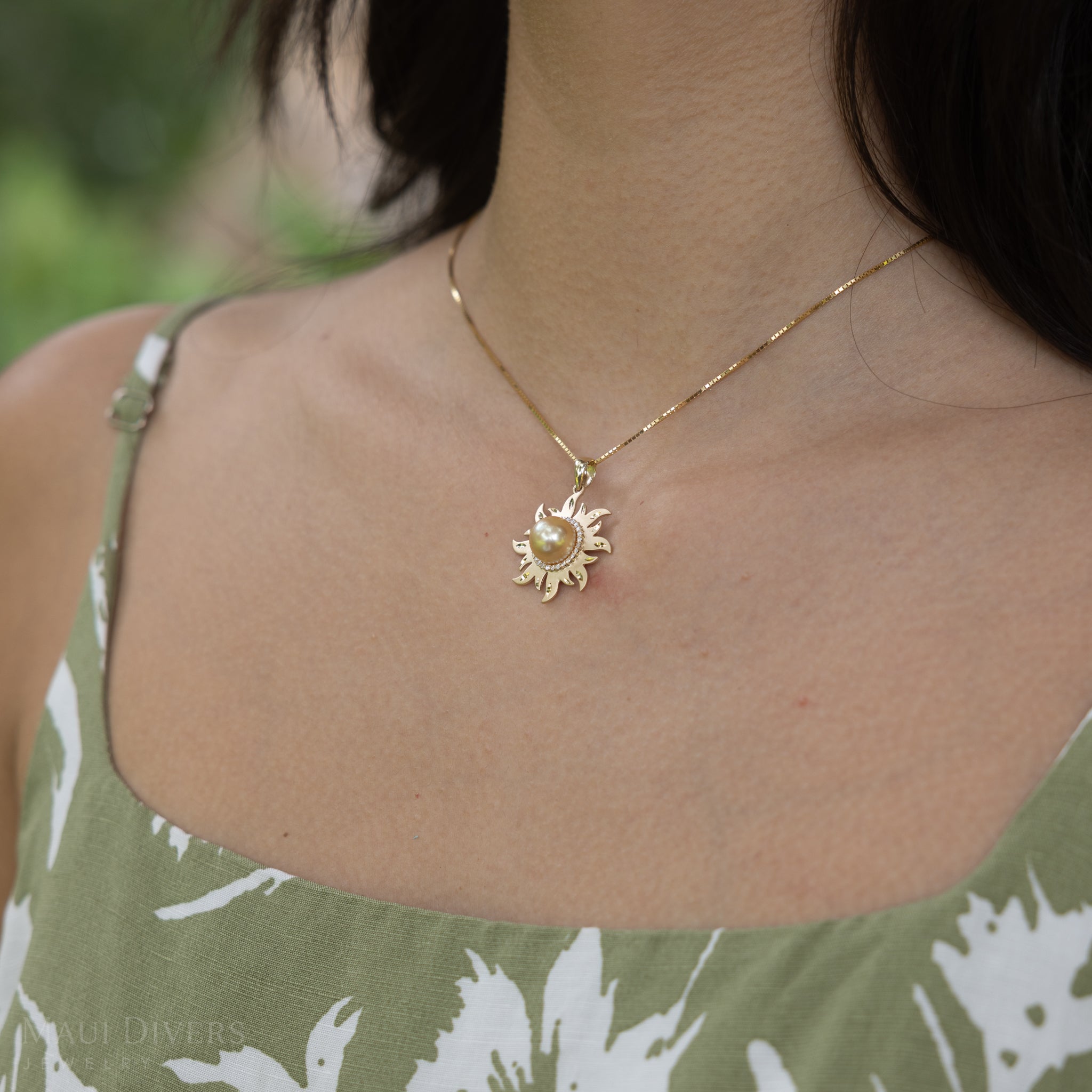 Side view of a diamond south sea gold sun pendant in 14k yellow gold worn on a woman's neck.