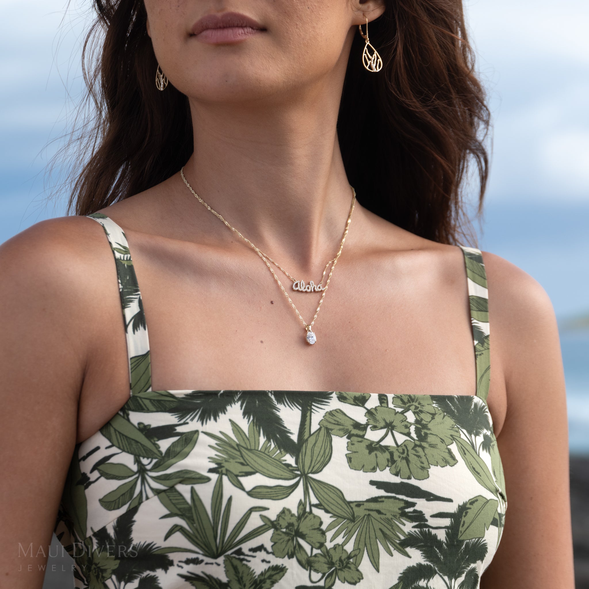 Close-up of a woman wearing a lab-grown diamond pendant on a Singapore chain and a diamond Aloha necklace 