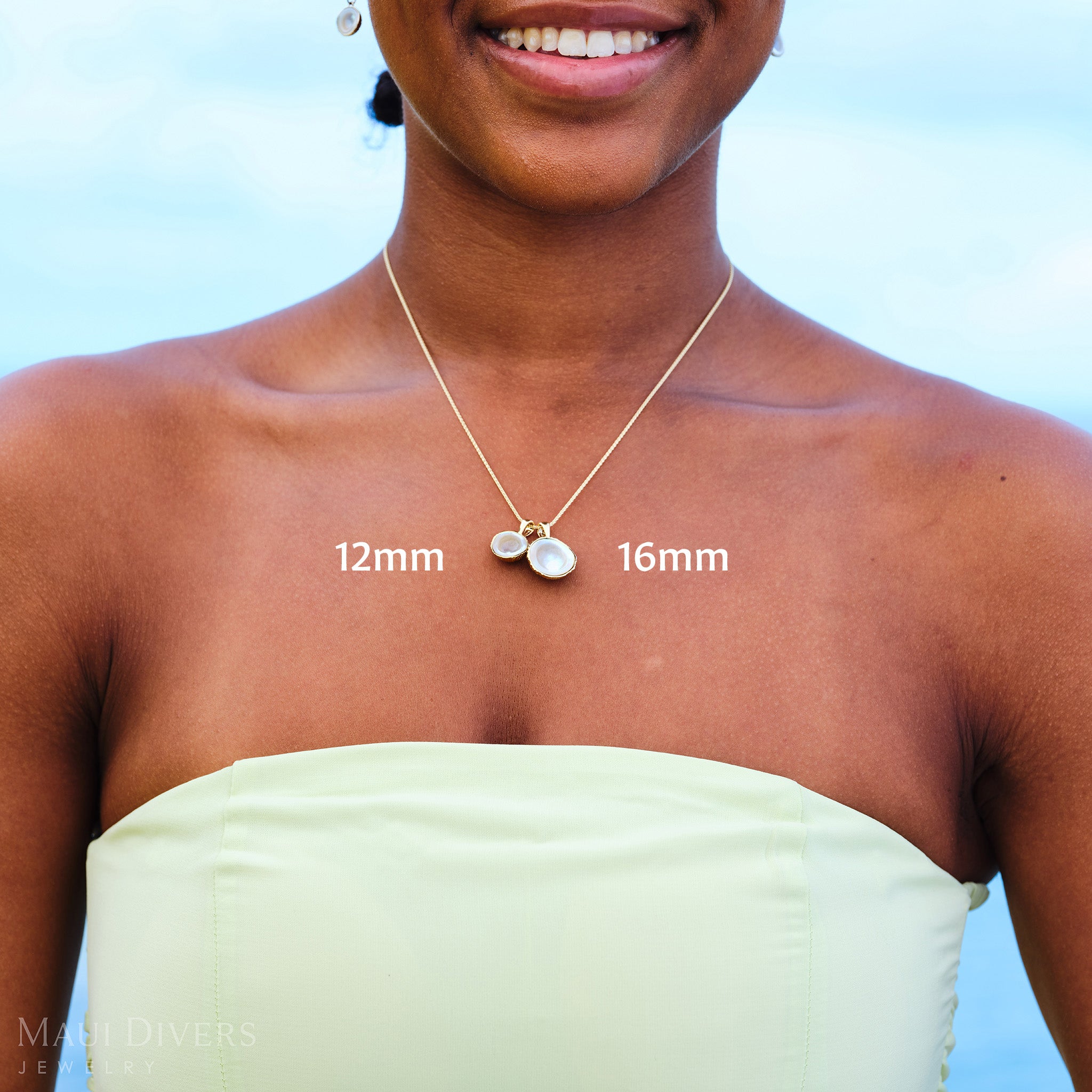 Woman in a pastel green top wearing a necklace with two Cute Fruits Coconut Mother of Pearl Pendants in 14k yellow gold, labeled 12mm and 16mm
