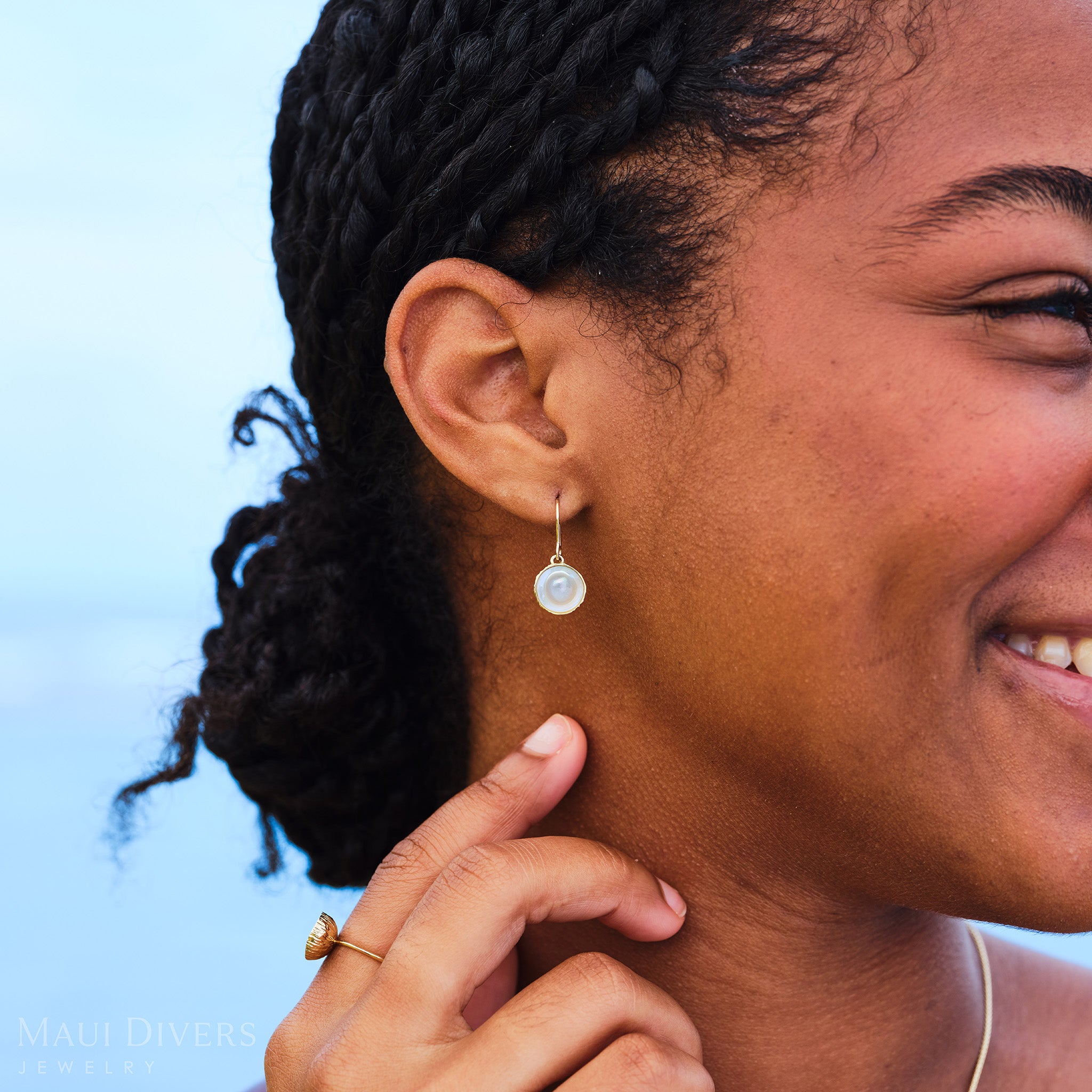 Close-up of a woman outdoors wearing Coconut Ring and Earring with Mother of Pearl center and Gold outer husk