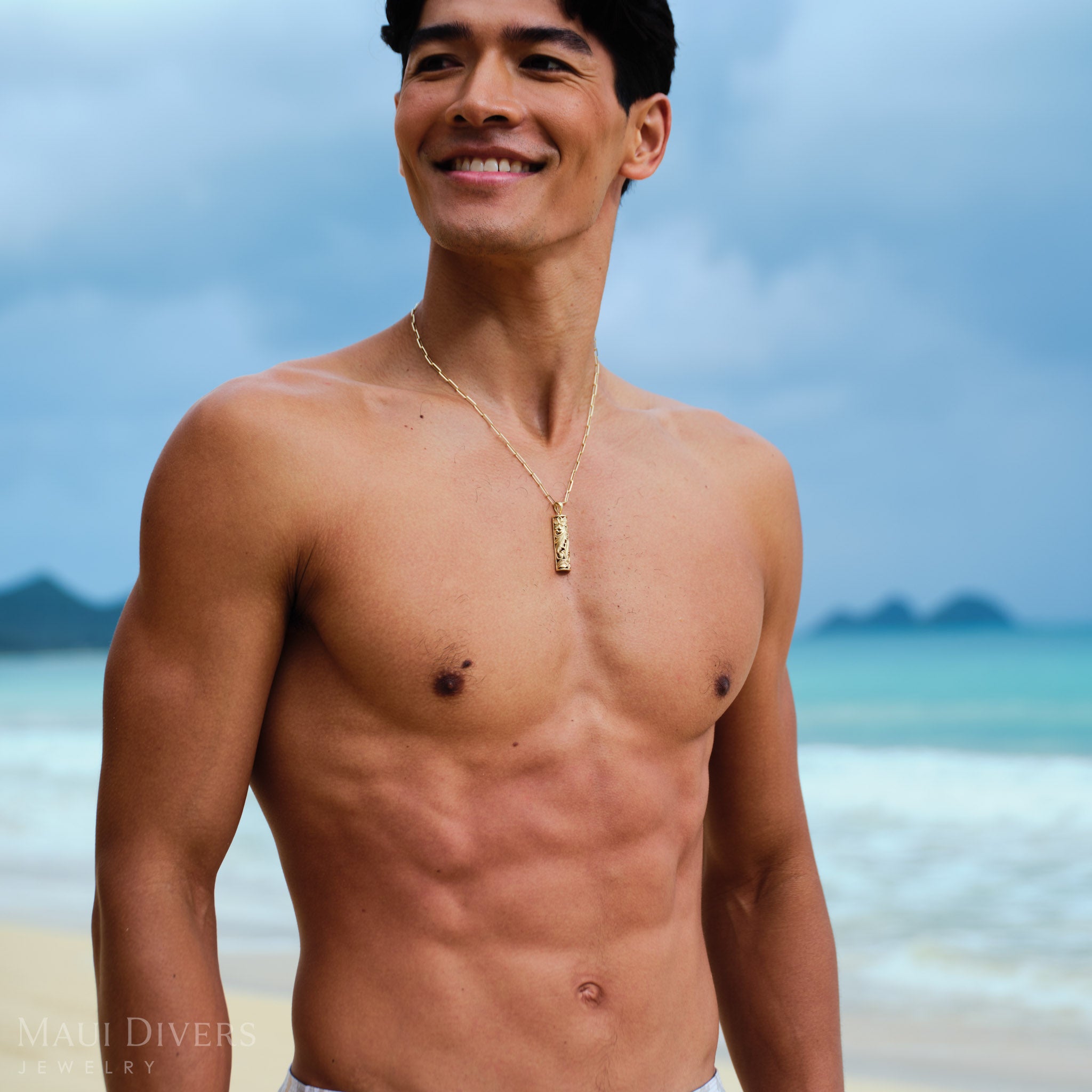 Man wearing a gold Hawaiian Heirloom Pendant on a Paperclip Chain on a beach