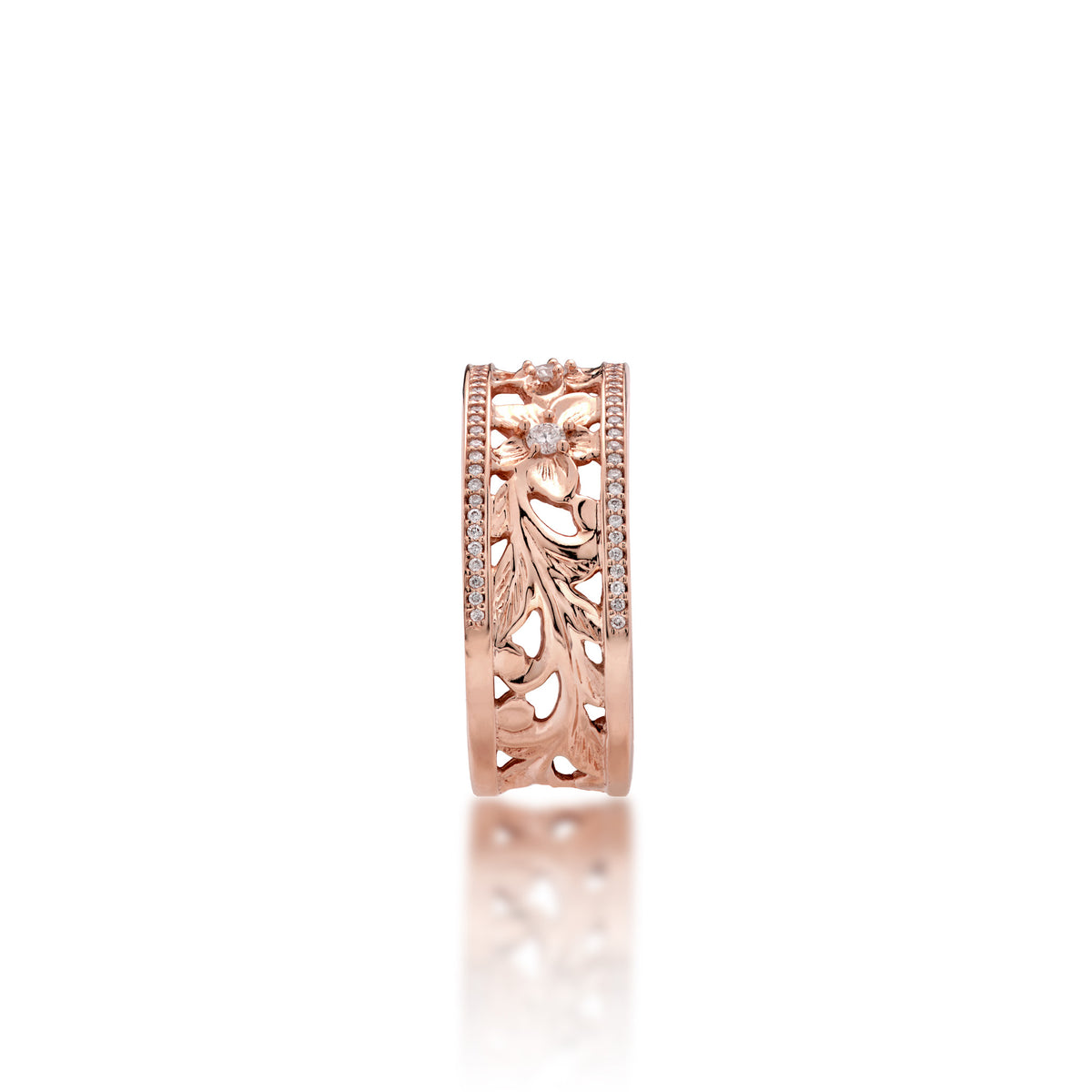 A side view of a 14k rose gold Hawaiian Heirloom Ring ring diamond-accented plumeria flowers at the top and fern and maile leaf scrollwork at the bottom and a row of pave set diamonds on each side of the band, shown on a white background