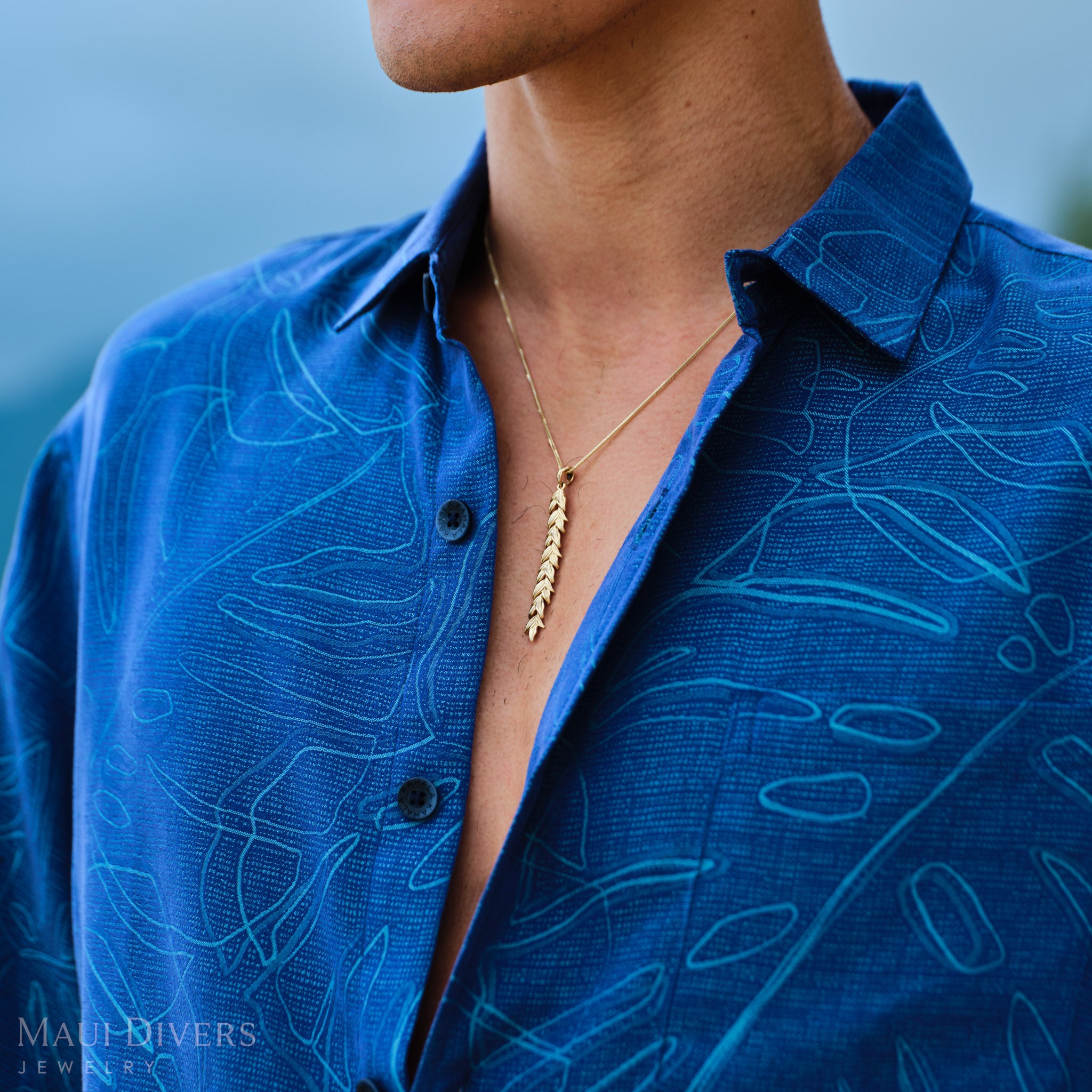 Man wearing a blue patterned shirt with a gold Maile Leaf Necklace
