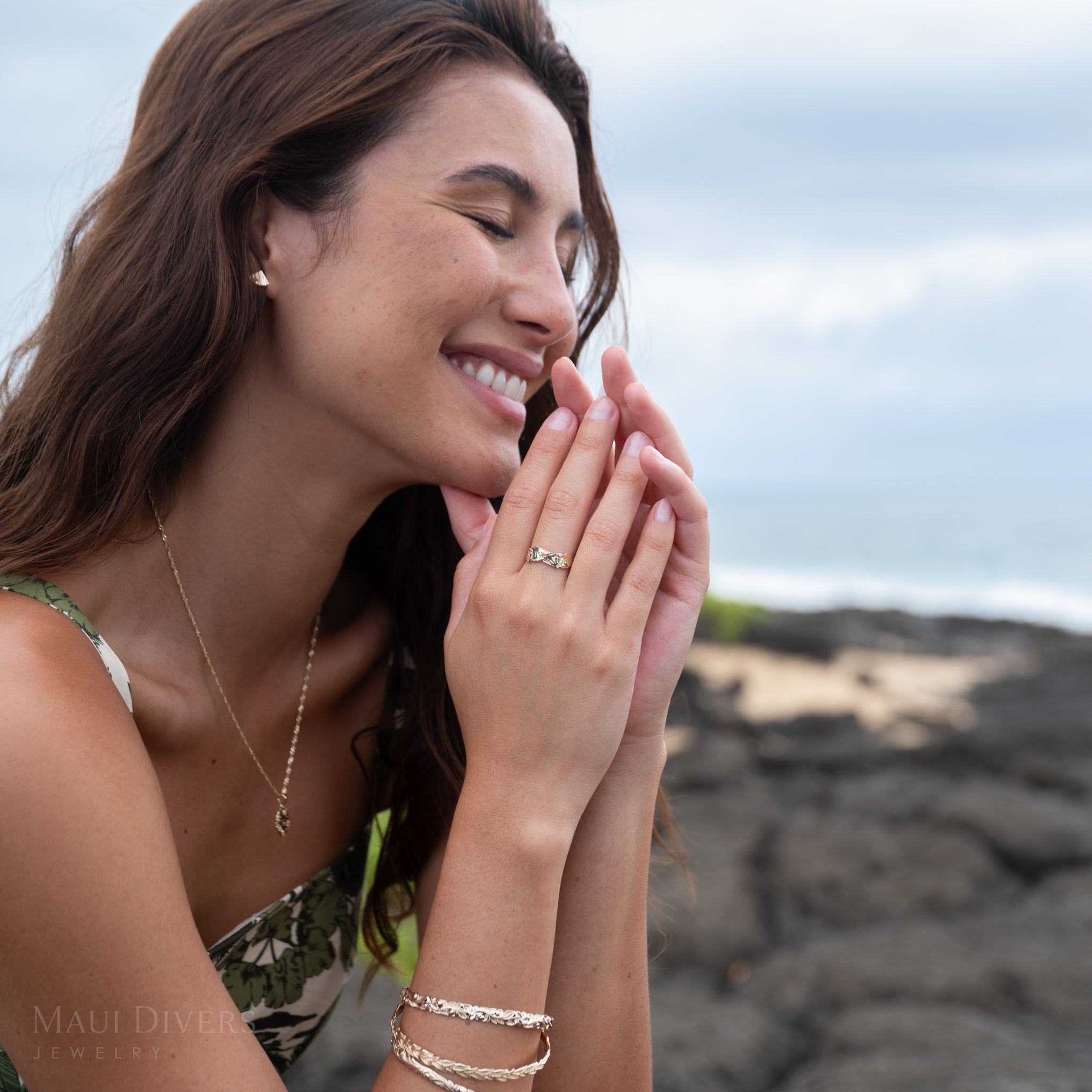 Woman with a pine slice, orange sapphire, and gold ring on her finger against a natural background