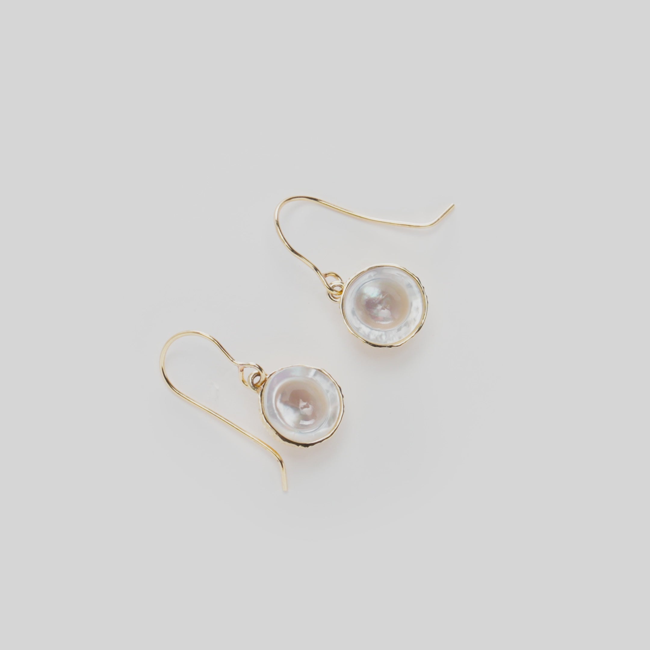 Close-up video of Cute Fruits Coconut Mother of Pearl Earrings in 14k yellow gold rotating on a white background